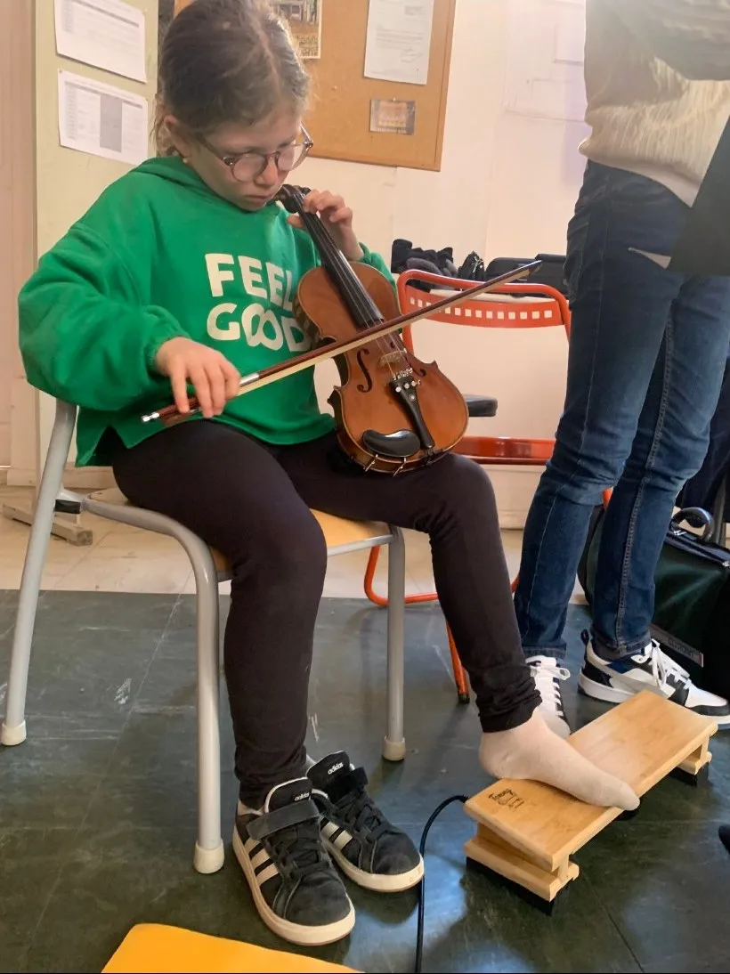 Une jeune violoniste joue, ses pieds posés sur une planche Tommy en bambou
